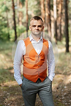 portrait of the groom in a gray suit and an orange vest