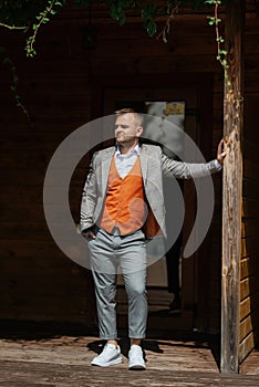 portrait of the groom in a gray suit and an orange vest