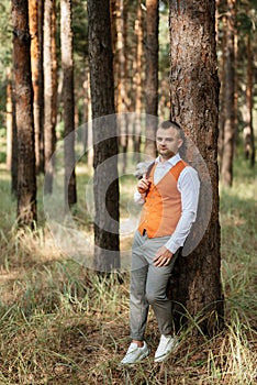 portrait of the groom in a gray suit and an orange vest