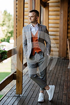 portrait of the groom in a gray suit and an orange vest