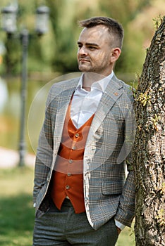 portrait of the groom in a gray suit and an orange vest