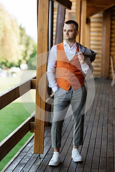 portrait of the groom in a gray suit and an orange vest