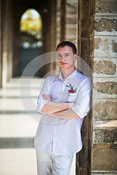 Portrait of the groom near the stone columns of the Catholic Church