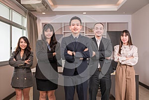 Portrait of group Asian business people in suit standing arms crossed and smiling looking on camera in office room