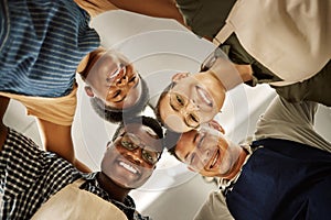 Portrait of group of fashion designers huddles together. Happy tailors united in a circle from below. Diverse