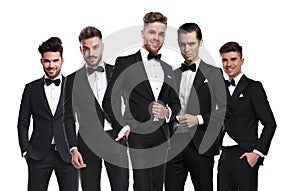 Portrait of group of five elegant men in tuxedoes standing
