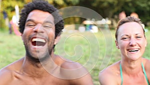 Portrait of group of friends sitting in nature, laughing at camera