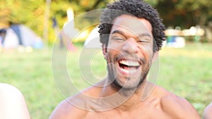 Portrait of group of friends sitting in nature, laughing at camera