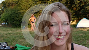 Portrait of group of friends sitting in nature at sunset, laughing at camera