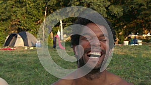 Portrait of group of friends sitting in nature at sunset, laughing at camera