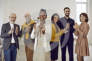 Portrait of group of multiethnic business people applauding and proudly smiling looking at camera.