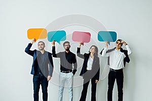 Portrait of a group of multiracial business people holding empty speech bubbles isolated over white background