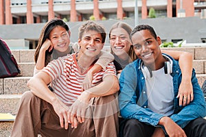 Portrait of a group of real multiracial high school students smiling and looking at camera sitting on the steps of a