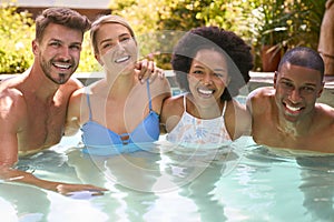 Portrait Of Group Of Smiling Multi-Cultural Friends On Holiday In Swimming Pool 