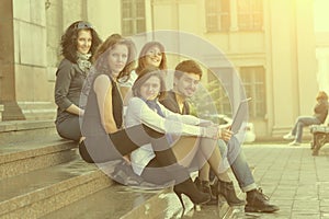 Portrait of a group of students sitting in front of the University