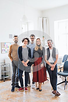 A portrait of group of young businesspeople standing in a modern office.