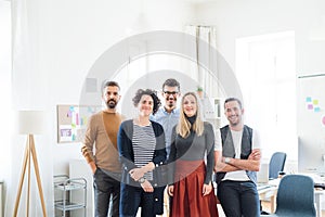 A portrait of group of young businesspeople standing in a modern office.