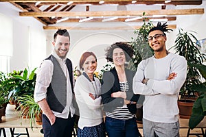 Group of young businesspeople standing in office, looking at camera.