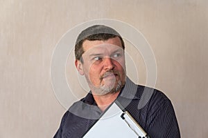 Portrait of a grown man holding a clipboard. A man with a short haircut and graying hair. White blank piece of paper clutched in