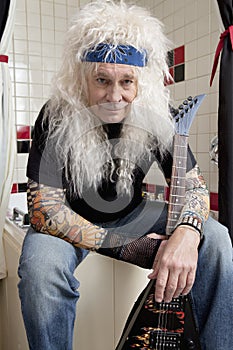 Portrait of guitarist sitting in bathroom