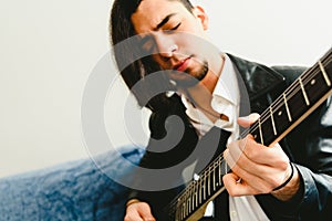 Portrait of guitarist with white shirt and expressive gesture of enjoyment of the music he is playing