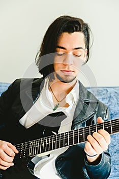 Portrait of guitarist with white shirt and expressive gesture of enjoyment of the music he is playing