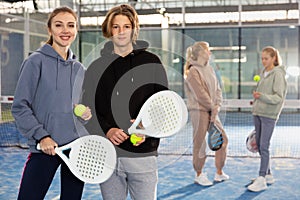 Portrait of guy and girl on an open court playing padel