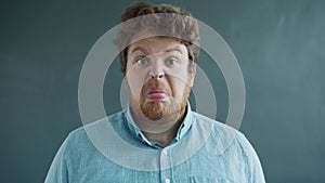 Portrait of guy showing tongue with hostile face then putting on glasses and looking at camera