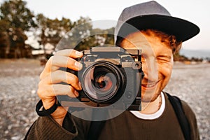 Portrait of a guy taking a photo with a professional camera. Close up portrait of photographer taking pictures with digital camera