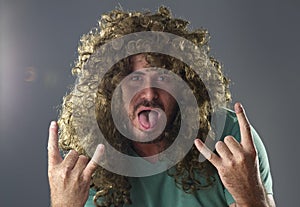 Portrait of a guy with a wig doing a rock and roll symbol