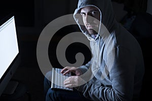 Portrait of hacker in the sitting in front of computer