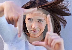 Portrait, hair and woman with finger frame, wall and focus for creative fashion photography. Perspective, hand gesture