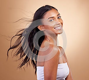 Portrait, haircare and salon for indian woman with beauty in brown studio background with glow. Hairstyle, happy face