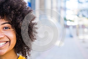 Portrait of half a face of one young beautiful cheerful African or American woman looking at the camera smiling and having fun.