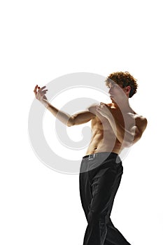 Portrait of half-naked handsome young man moves his hands smoothly against white studio background. Model looks as