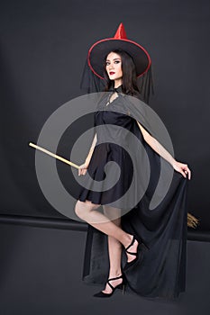 Portrait of Halloween Witch girl, Beautiful young Asian women holding witch`s broom over black background