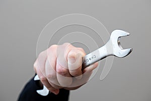 A portrait of a hand of a person or construction worker holding a metal chrome open end wrench tool