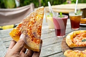 Portrait of hand with a slice of pizza look a yummy with yellow cheese