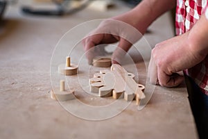 Portrait hands carpenter wood element wheel dinosaur toy at