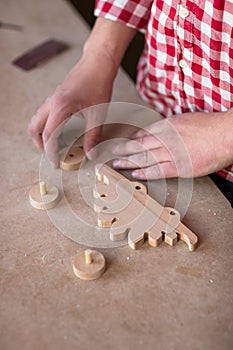 Portrait hands carpenter wood element wheel dinosaur toy at