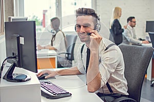 Portrait of handsom customer support phone operator in headset at office.