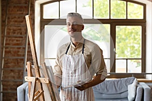 Portrait of handsome 40s man drawing on canvas.