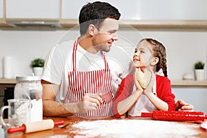 Portrait of handsome affectionate father embraces her little daughter, make cookies together, being in good mood