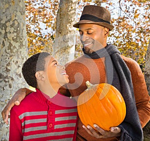 Portrait of Handsome African-American father and happy son choosing a pumpkin in Autumn.