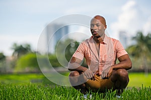 Portrait of handsome African American man in summer casual clothing. Squatting position and smiling off camera with blurry