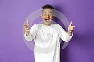 Portrait of handsome african-american young man, reaching hands forward to receive something, looking amazed and happy