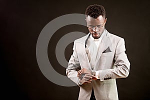 Portrait of handsome afro businessman looking at the watch on his arm