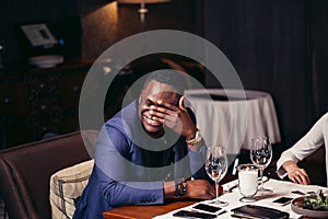Portrait of handsome afroamerican man in blue jacket drinking wine at restaurant