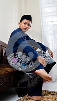 A portrait of handsome Asian Malay man wearing a blue traditional Baju Melayu with songkok and kain sampin photo
