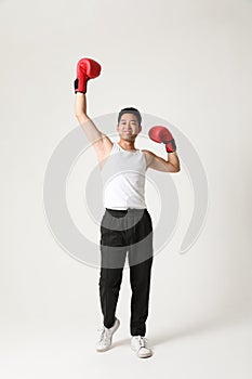 Portrait of a handsome Asian man with red boxer gloves posing indoor. Vertical.